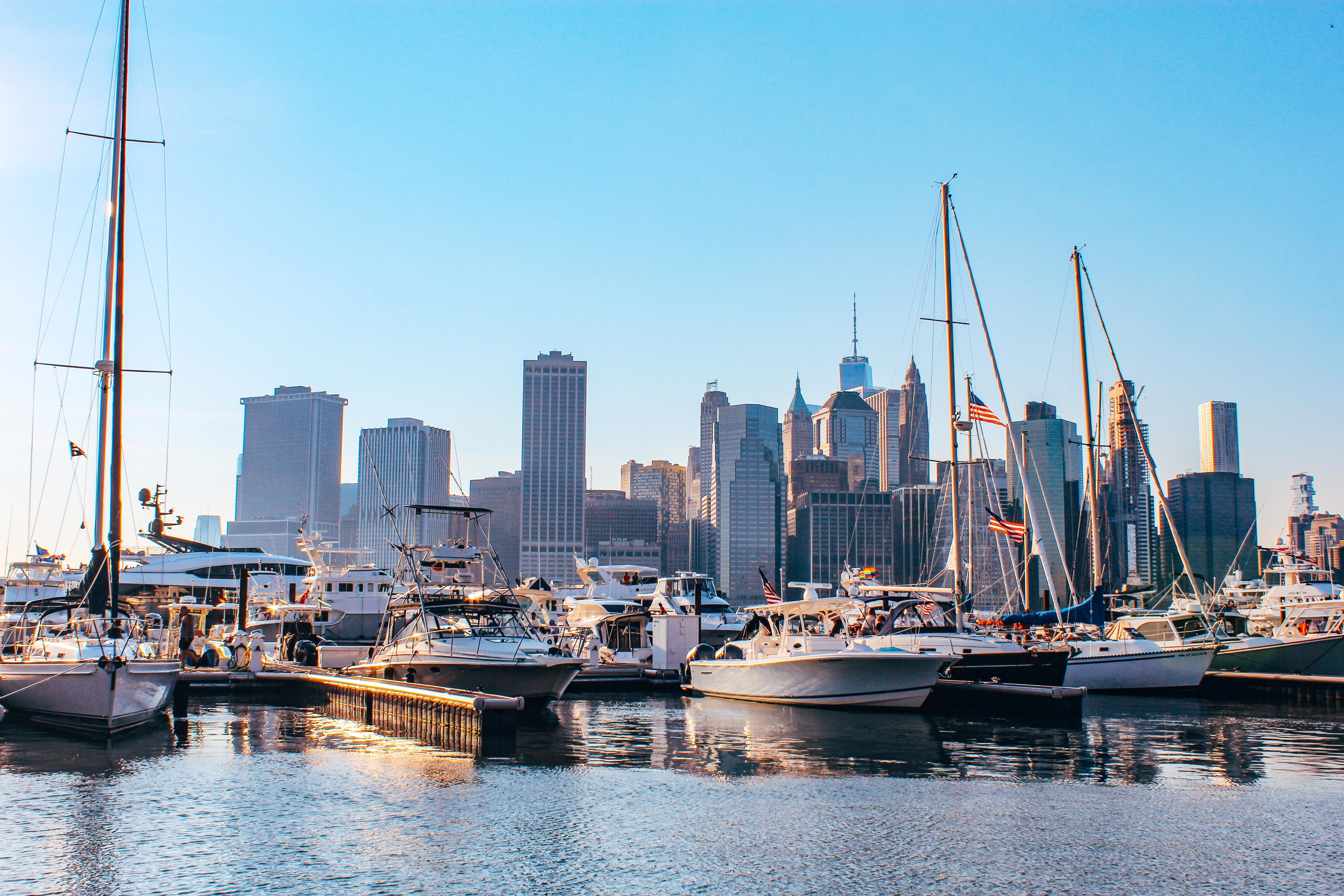 Boats docked at a marina with the New York City skyline behind