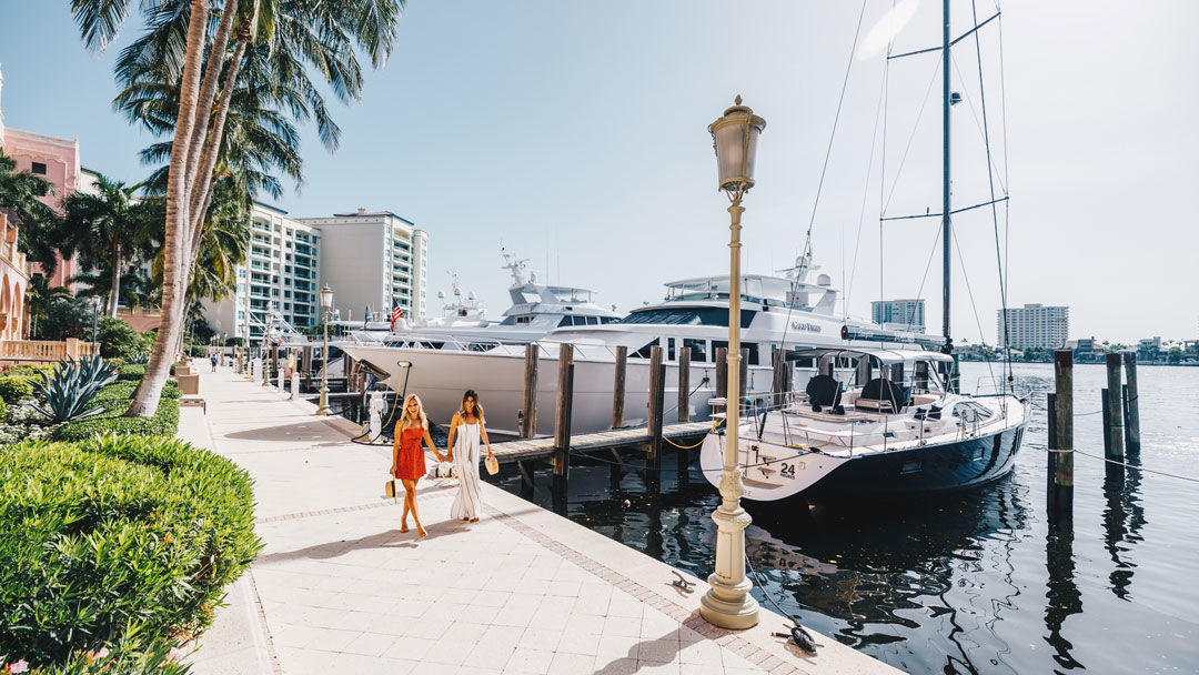 Yachts docked along a waterfront marina promenade in Boca Raton