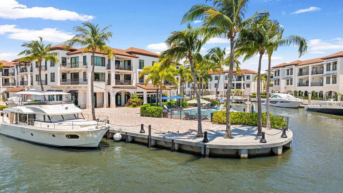 Boats docked at a palm-lined waterfront marina in Naples, Florida